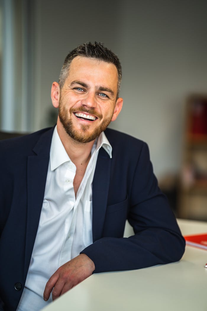 Services Business professional in suit smiling confidently in a modern office environment.