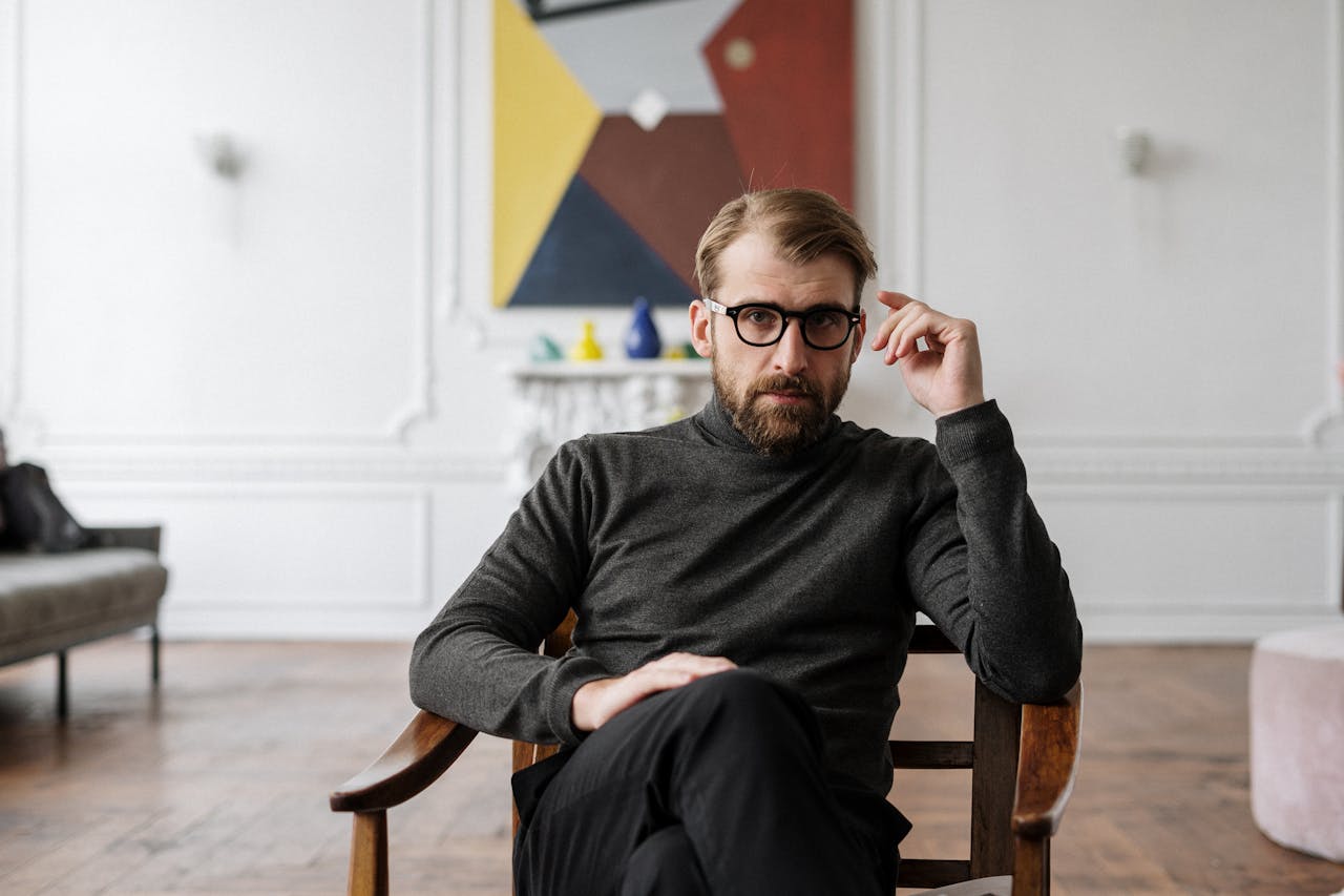 Home Man with glasses seated in modern interior with abstract art.