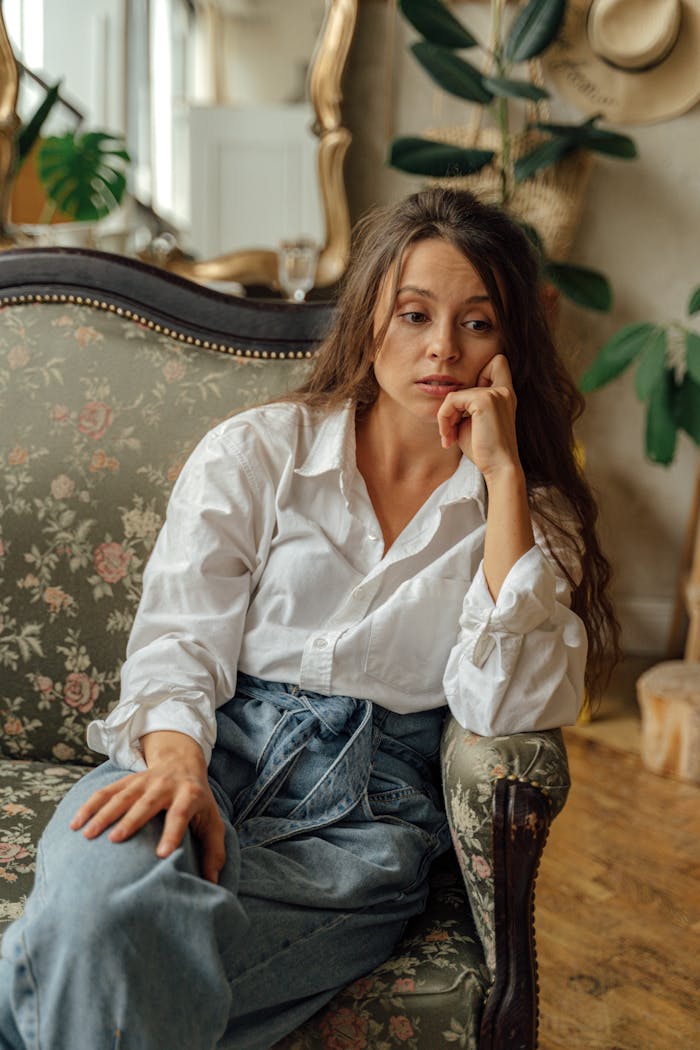 The Art of Drawing Readers In: Your attractive post title goes here A woman in a casual outfit sits thoughtfully on a floral vintage sofa indoors.