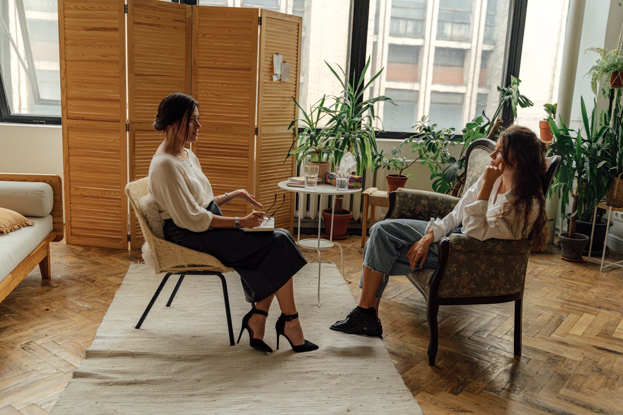 Services Two women sit in a therapy session, creating a tranquil and professional environment.